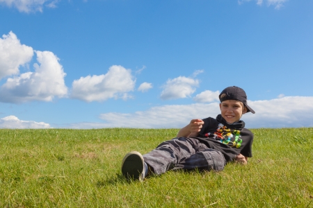The boy lies on meadow  Blue sky with clouds の写真素材