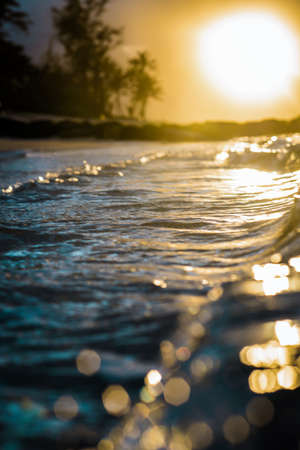Sunset on the beach. Waves in the sea. The sun is reflected in the water.