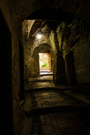 Narrow and mysterious road in a mountain town. Narrow street with houses and walls made of stone and ancient cobblestone.の写真素材