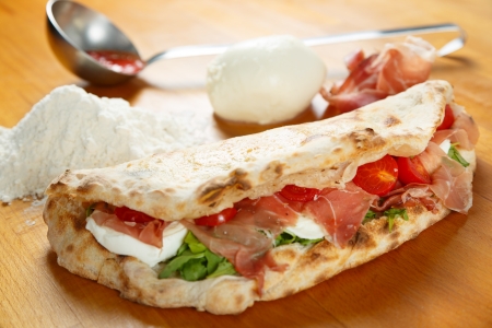 Typical Italian Pizza cooked in electric oven with ingredients in the background on a wood tableの写真素材