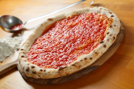 Typical Italian Pizza cooked in electric oven with ingredients in the background on a wood tableの写真素材