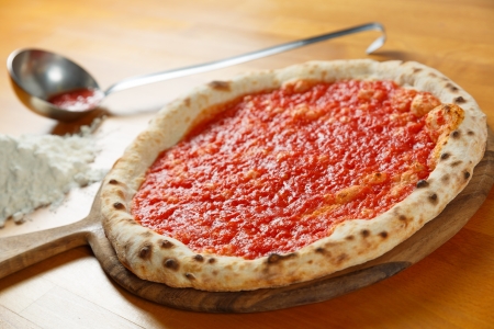 Typical Italian Pizza cooked in electric oven with ingredients in the background on a wood tableの写真素材