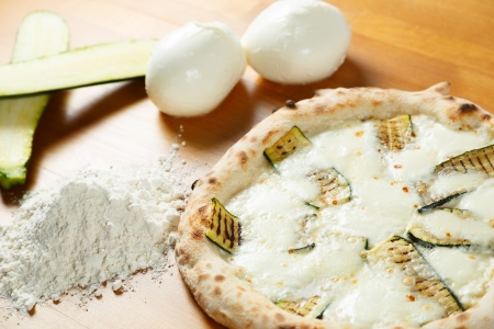 Typical Italian Pizza cooked in electric oven with ingredients in the background on a wood tableの写真素材