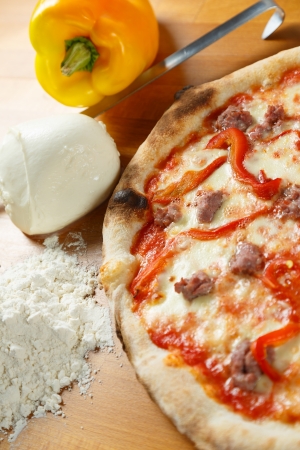 Typical Italian Pizza cooked in electric oven with ingredients in the background on a wood tableの写真素材