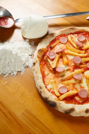 Typical Italian Pizza cooked in electric oven with ingredients in the background on a wood tableの写真素材