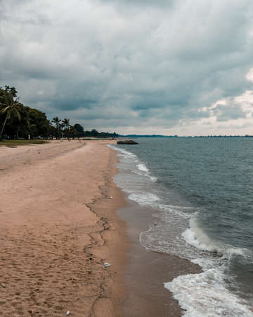 Line intersection where the crashing waves of the sea meets the sandy beach of East Coast Part, Singaporeの写真素材