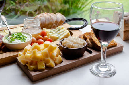 Delicious Charcuterie Board with snacks cheese, toast, ham, blue cheese, almonds, caramelized onions, green onion, honey, toast. Flat-lay view. Family, friends holiday gathering. Argentine Tradition. Picada. At home with garden viewの写真素材
