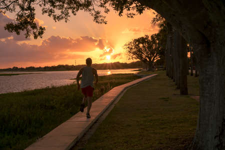 Young man running in a beautiful sunset by the lake. Sport conceptの写真素材