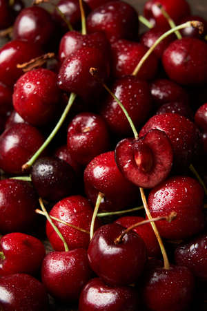 Close up of pile of sweet red cherries with stalks and leaves. Large collection of fresh red...