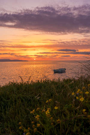 Boat on the bank of the salt pan or pond during sunset in the old traditional salt works close to city Trapani in Sicily island. Italy landscape. Salt pans in traditional salt production in Trapani, Sicily, italyの写真素材
