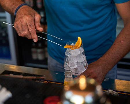 Spritz traditional cocktail with alcohol being prepared by unrecognizable man in a beach bar....