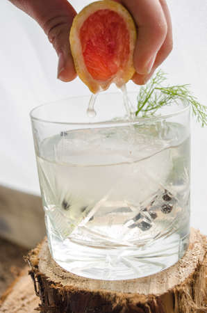 Making a Pink grapefruit and rosemary gin cocktail served in prepared glass on a tropical beach bar. Drink concept.の写真素材
