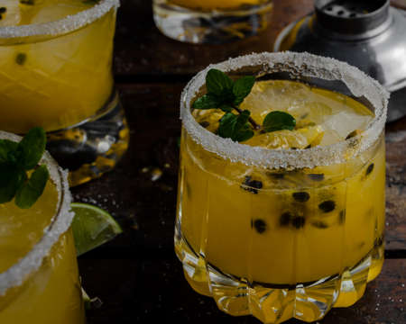 Fresh and Tropical cocktail with passion fruit, lime, mint and ice on a wooden background. Cold summer drink. Beverages and drink concept.の写真素材