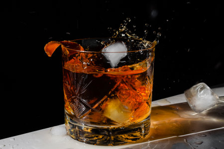 Luxury still life of whiskey glass, on the rocks, with ice cube falling into Glass of Whiskey, Freeze Motion. Splashの写真素材