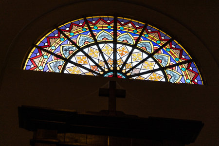 Vibrant stained glass window in a historic church, featuring intricate religious motifs and colorful...