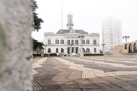 Foggy view of Independence Square in Azul featuring a historic church and equestrian monument. A...