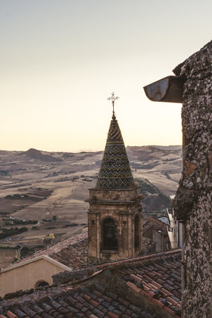Decorated ceramic bell tower above rooftops in rural Italy at duskの写真素材