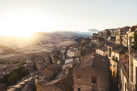 Terracotta rooftops overlooking rolling hills at sunsetの写真素材