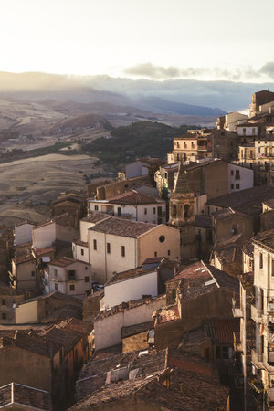 Terracotta rooftops overlooking rolling hills at sunsetの写真素材