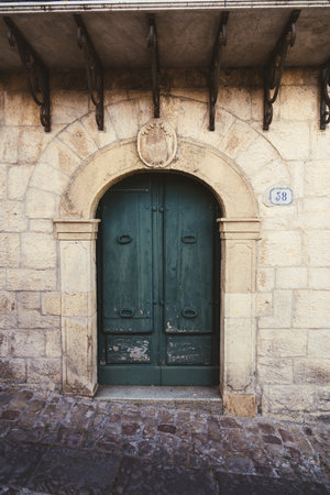Old green wooden door in stone building with arched frameの写真素材