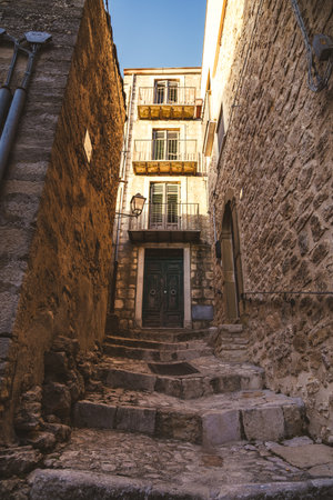 Narrow alley with stone steps leading to old building with balconiesの写真素材