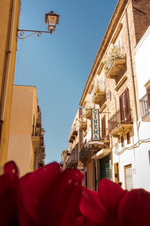 Old cinema sign on a narrow traditional Italian street with balconies and warm sunlightの写真素材
