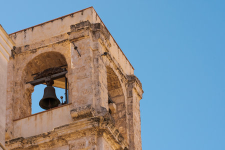 Close-up of an old bell tower from a historic stone church under clear blue skyの写真素材