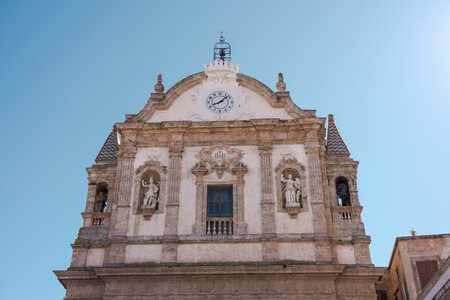 Front view of a baroque church with statues, bell tower, and central clock in Italyの写真素材