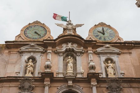 Baroque facade detail with clocks statues and flag