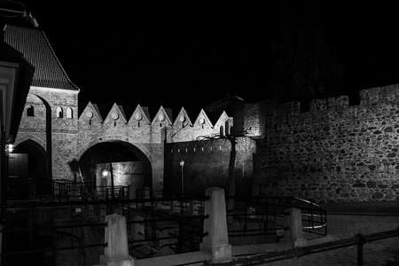 Old town fragment of ToruÅ at night, defensive monuments with an entrance gate, paved roadの写真素材