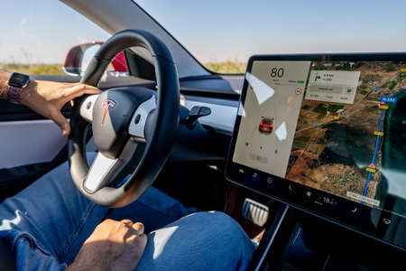 Murcia, Spain - OCTOBER 26, 2019: Young man is driving a Tesla car and is holding the steering...