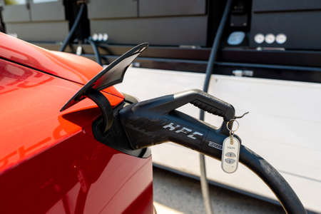 Murcia, Spain - July 31, 2021: Red Tesla Model 3 electric car is charging at Porsche and Iberdrola...