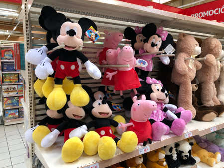 MURCIA, SPAIN - NOVEMBER 2, 2021: Many stuffed dolls are displayed on a shelf in a spanish supermarket in the toy aisle. The most famous are Mickey, Minnie and Peppa Pig..のeditorial素材