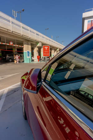MURCIA, SPAIN - FEBRUARY 2, 2021: A red Tesla Model 3 is parked in a Supercharger station in a mall...