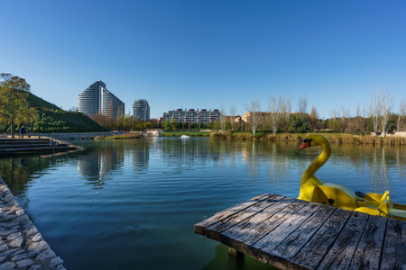 A lake inside CabeceraÂ´s Park in Valencia city with buildings at background and a big yellow duckの写真素材