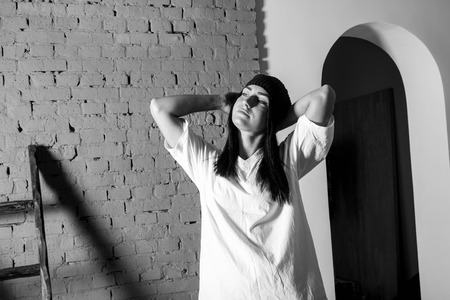 European girl against a brick wall in a t-shirt and hat fashion styleの写真素材