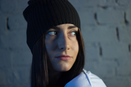 European girl against a brick wall in a t-shirt and hat fashion styleの写真素材