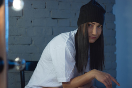 European girl against a brick wall in a t-shirt and hat fashion styleの写真素材