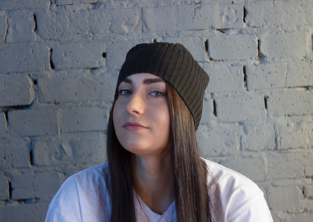 European girl against a brick wall in a t-shirt and hat fashion styleの写真素材