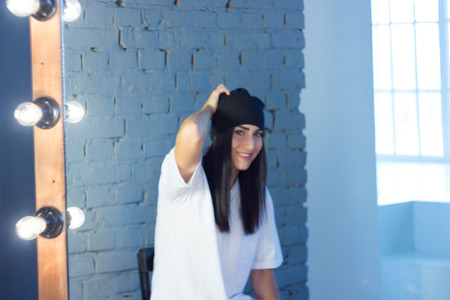 European girl against a brick wall in a t-shirt and hat fashion styleの写真素材