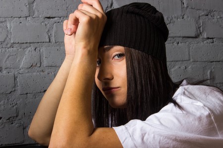 Girl in a white t-shirt and a black hat fashion style clothing feelings against a brick wallの写真素材