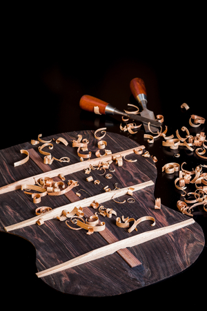 Back of guitar under construction with chisels and wood chips