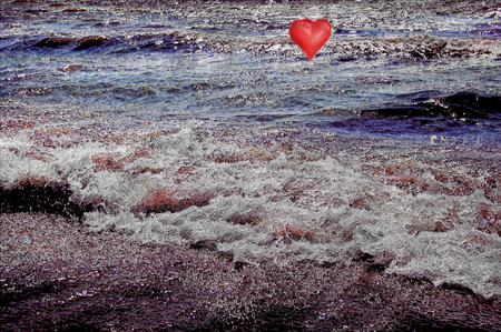 A red air balloon-heart at the blue sea,a sun light,a wavesの写真素材