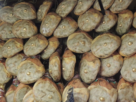 the back of hams hanging in bulk for sale in a shopの写真素材