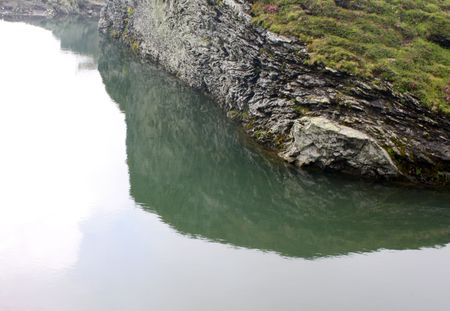 Reflection of a big rock in water of Balea lakeの写真素材
