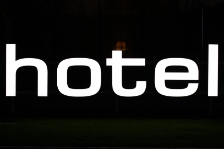 Illuminated hotel sign from plexiglass against black backgroundの写真素材