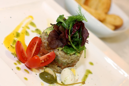 Salmon tartar with salad and capersの写真素材