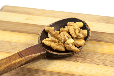 Walnut kernels into an old wooden spoon on a wooden boardの写真素材