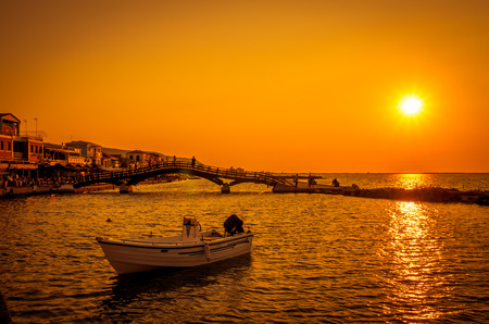 Sunset over town of Lefkas in Lefkada Island, Greece. Sunset scene in Levkas town. There are a bridge over the water and a boat.の写真素材