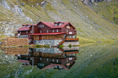 BALEA LAKE, ROMANIA - SEPTEMBER 19, 2015: Beautiful view of Balea Lake cottage on Fagaras Mountains, Carpathian, Romania. The image of the chalet is reflected in the lake.のeditorial素材
